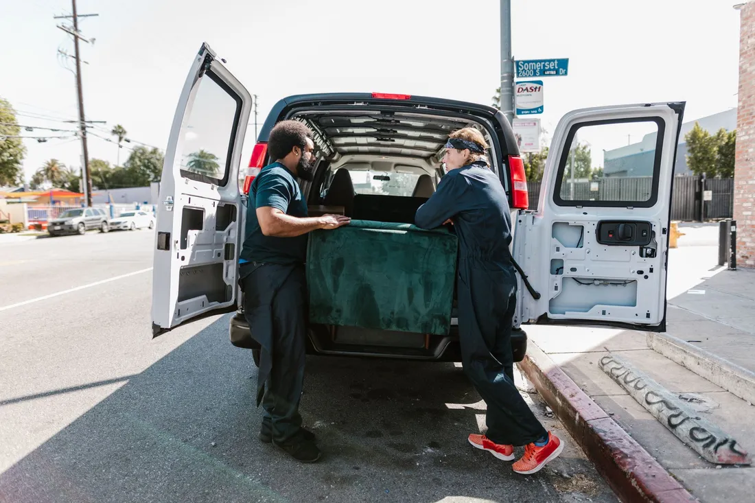 Transporter wird an einer Straße mit Möbeln und Kartons beladen